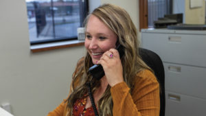 A woman in an office smiles as she is on the phone with a customer..